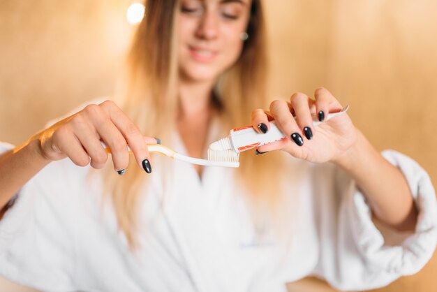 Jonge vrouw met in hand tandenborstel en tandpasta. mondhygiëne in de ochtend, gebitsreiniging