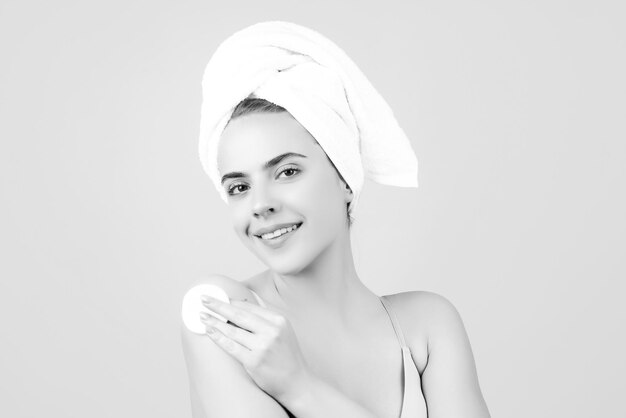 Jonge vrouw met kalm gezicht geniet van badprocedures gewikkeld met een handdoek op het hoofd geïsoleerd op een studioachtergrond