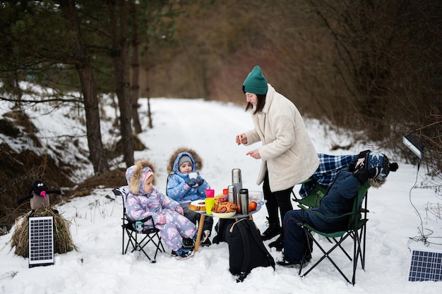 Jonge vrouw met kinderen in het winterbos op een picknick Moeder en drie kinderen