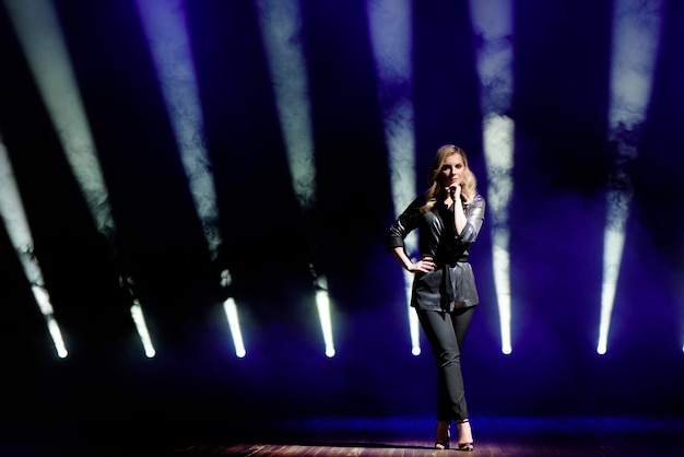 Jonge vrouw met kleurrijke lichten op concert op het podium.