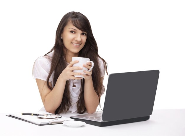 Jonge vrouw met kopje thee zittend op de werkplek