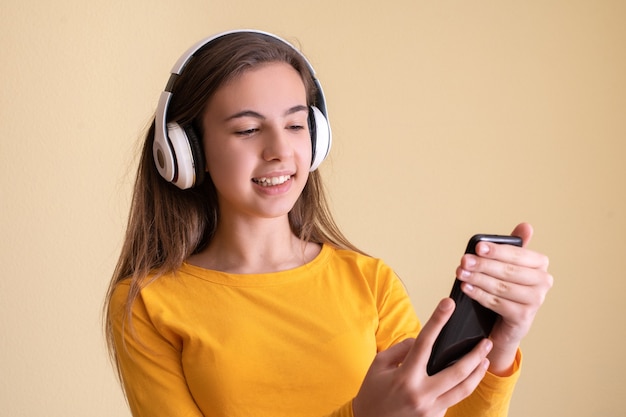 Jonge vrouw met koptelefoon dansen op gele achtergrond