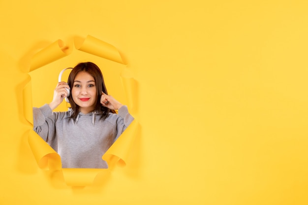 jonge vrouw met koptelefoon op gescheurd geel papier achtergrondgeluid audio