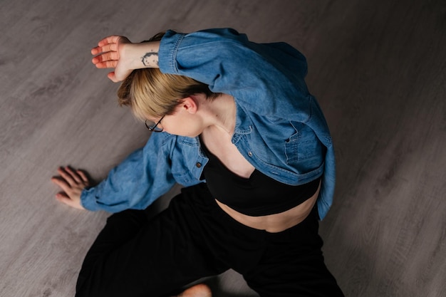 Jonge vrouw met kort haar dansen op de vloer binnenshuis Meisje doet yoga-oefening in studio