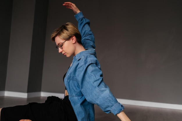 Jonge vrouw met kort haar dansen op de vloer binnenshuis Meisje doet yoga-oefening in studio
