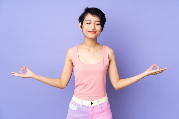 Jonge vrouw met kort haar over paars in zen pose