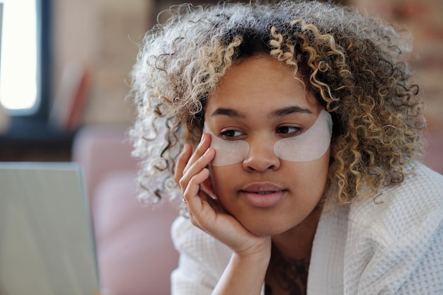 Jonge vrouw met kort krullend haar met ooglapjes op het gezicht