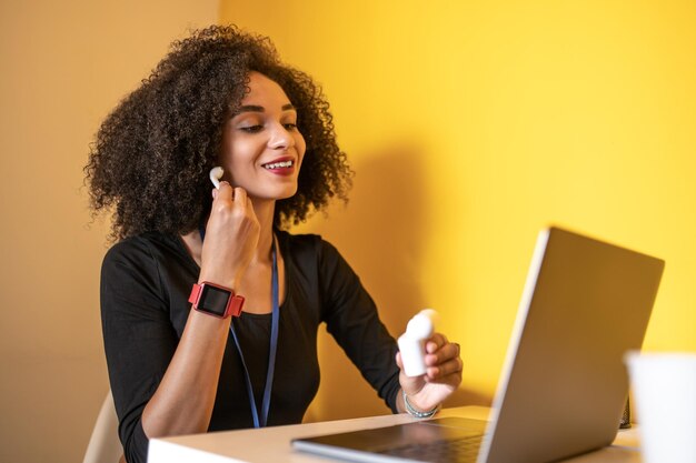 Jonge vrouw met krullend haar die draadloze oortelefoons opzet