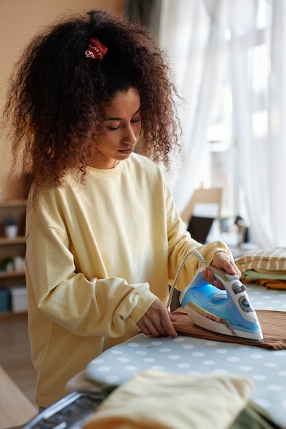 Jonge vrouw met krullend haar die kleren strijkt