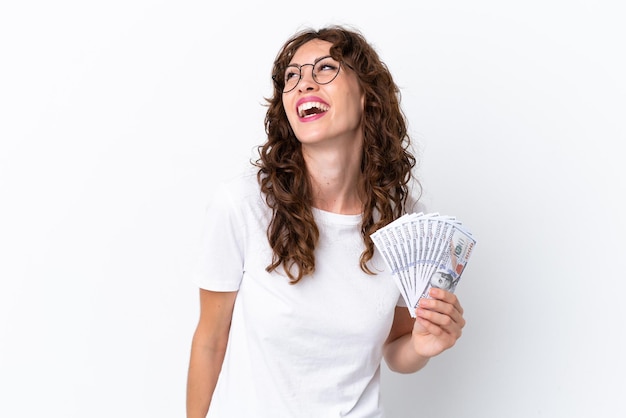 Jonge vrouw met krullend haar die veel geld geïsoleerde achtergrond op witte achtergrond neemt lachen