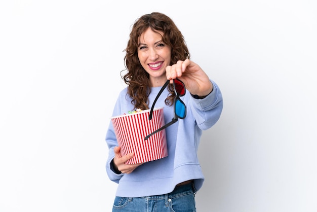 Jonge vrouw met krullend haar geïsoleerd op een witte achtergrond met 3D-bril en met een grote emmer popcorns