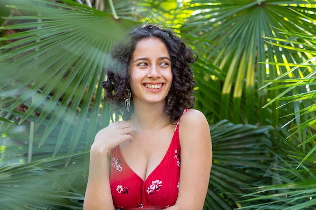 Jonge vrouw met krullend haar genietend in een paradijselijk park