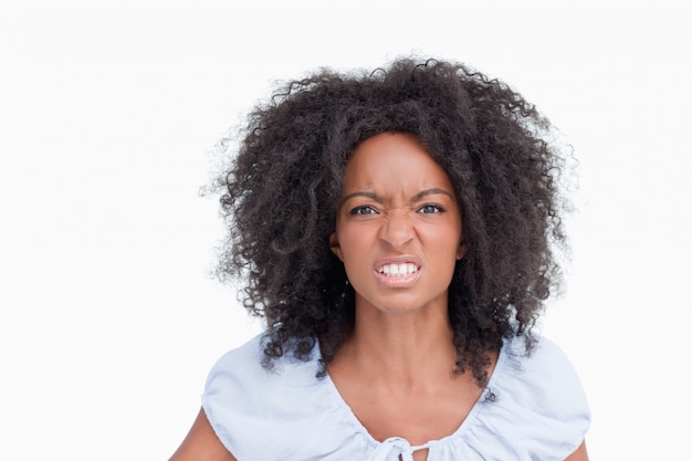 Jonge vrouw met krullend kapsel dat tanden toont om op haar woede te wijzen