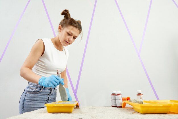 Jonge vrouw met kwast schilderij muur in een nieuw huis woondecoratie concept