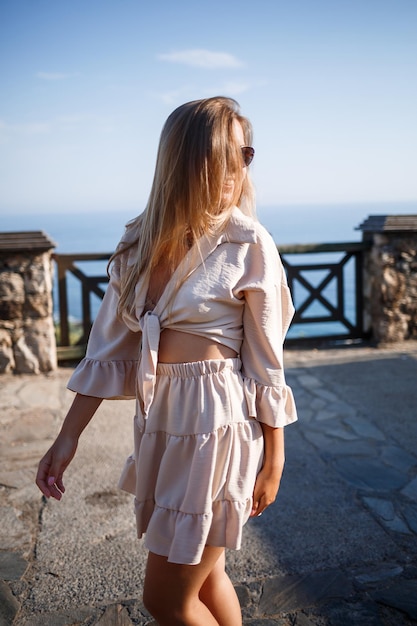 Jonge vrouw met lang blond haar in een lichte top en rok loopt op een zonnige zomerdag