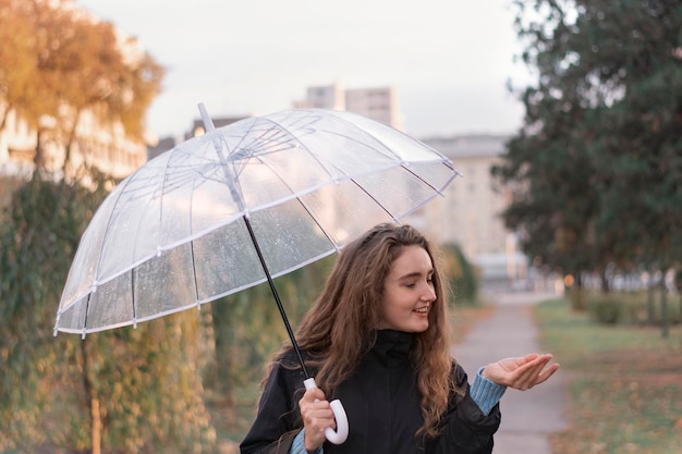 Jonge vrouw met lang bruin haar permanent met paraplu in park Meisje met een paraplu op bewolkte herfstdag