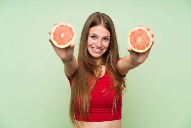 Jonge vrouw met lang haar die een grapefruit houden