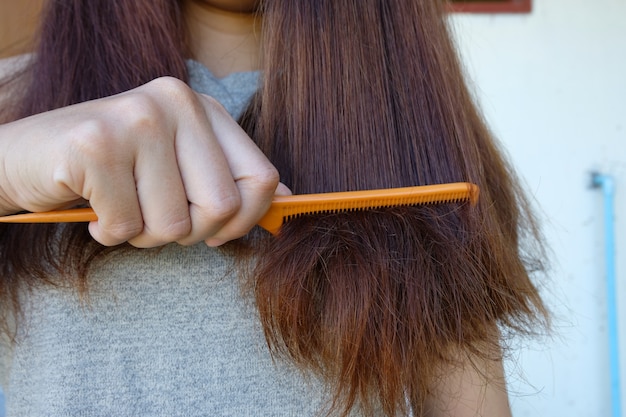 Jonge vrouw met lang haar in hand kam met borstel