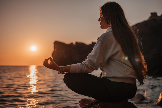 Jonge vrouw met lang haar in sportkleding en armbanden in boho-stijl die buiten op yogamat oefent