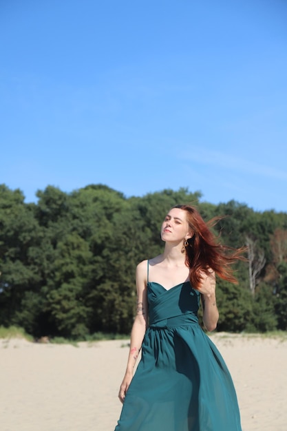 Jonge vrouw met lang rood haar op het strand