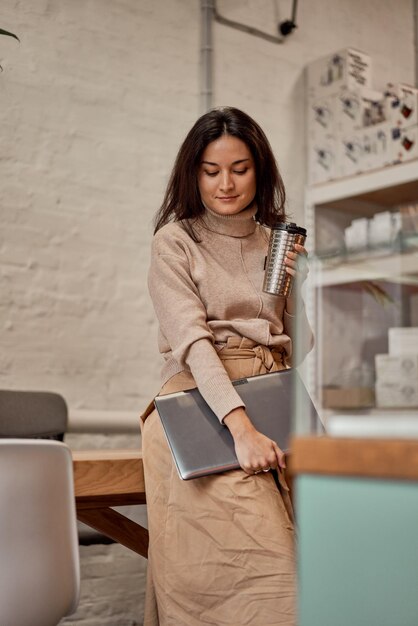 Jonge vrouw met laptop en warme drank