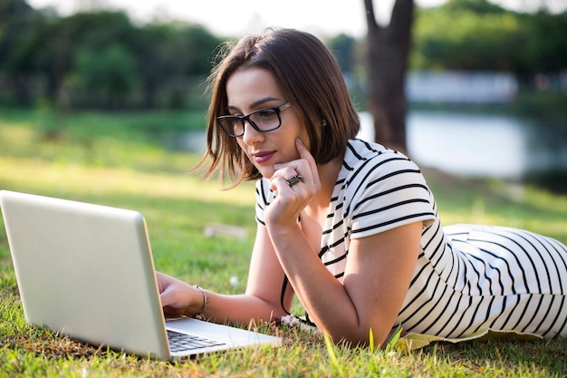 Jonge vrouw met laptop in park