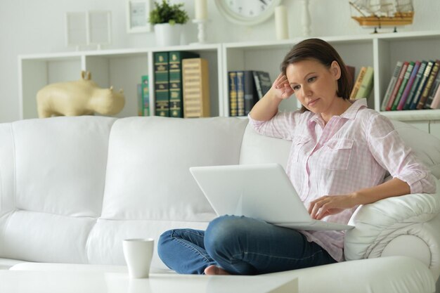 Jonge vrouw met laptop op haar knieën