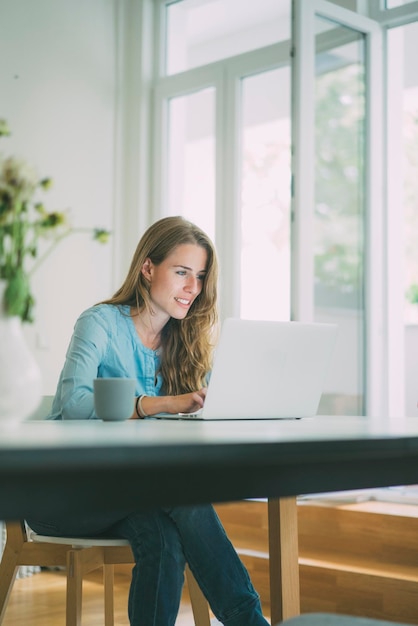 Jonge vrouw met laptop thuis