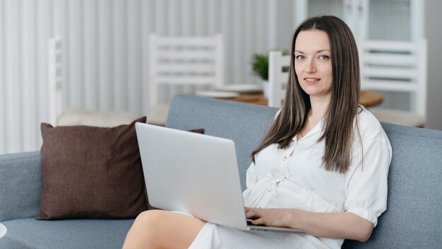 Jonge vrouw met laptop zittend op de bank