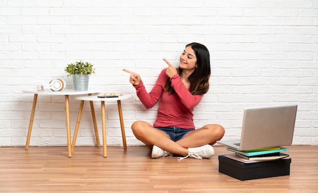 Jonge vrouw met laptop zittend op de vloer