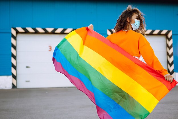 Jonge vrouw met LGBT-vlag en beschermend masker