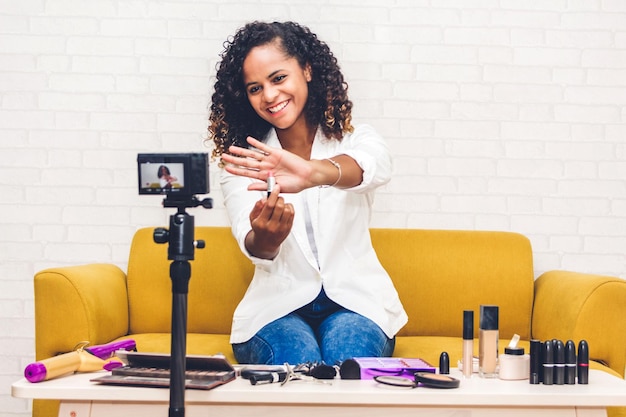 Jonge vrouw met make-up tijdens het opnemen op camera tegen de muur