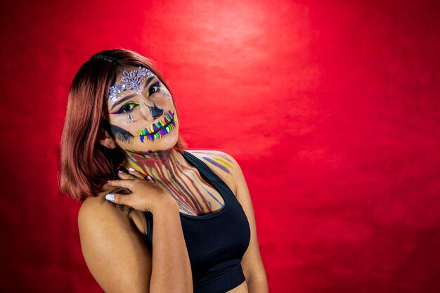 Jonge vrouw met make-up voor halloween party kostuum partij rode achtergrond