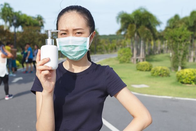 Jonge vrouw met medisch beschermend masker en een alcohol in de hand houden