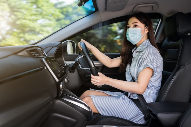 jonge vrouw met medisch masker autorijden. voor de bescherming van covid-19 (coronavirus) pandemie