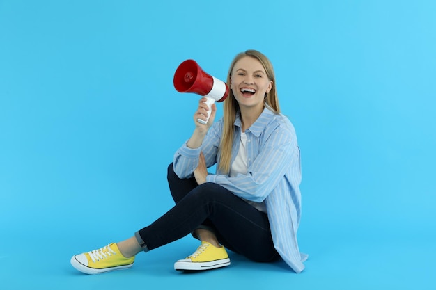 Jonge vrouw met megafoon op blauwe achtergrond