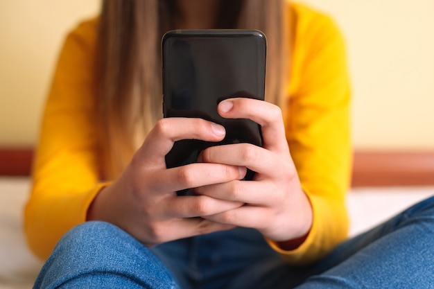 Jonge vrouw met mobiele telefoon die in bed ligt