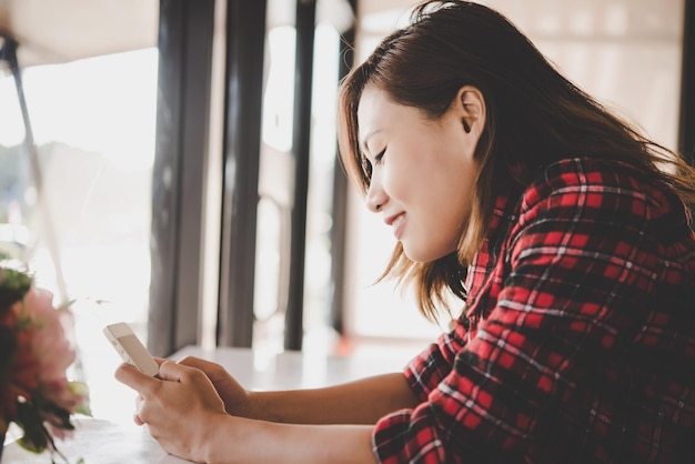 Jonge vrouw met mobiele telefoon op tafel