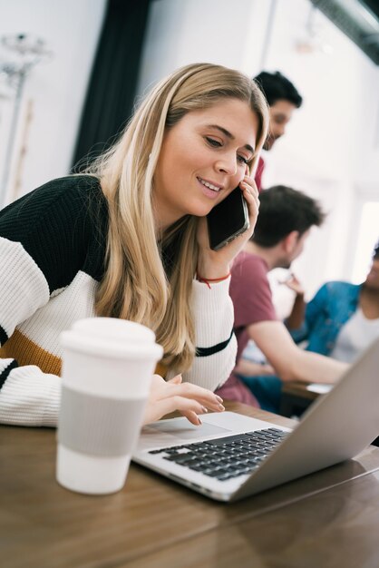 Foto jonge vrouw met mobiele telefoon terwijl ze in de bibliotheek zit