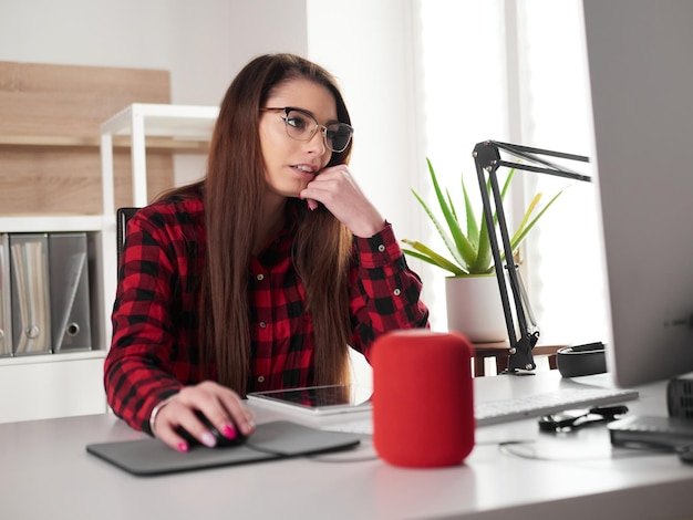 Jonge vrouw met mobiele telefoon terwijl ze op tafel zit