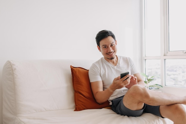 Jonge vrouw met mobiele telefoon terwijl ze thuis op bed ligt