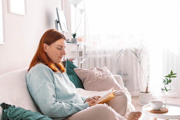 Jonge vrouw met mobiele telefoon terwijl ze thuis op bed zit