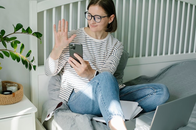 Jonge vrouw met mobiele telefoon terwijl ze thuis op de bank zit