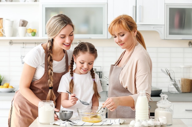 Jonge vrouw met moeder en dochter die in keuken koken