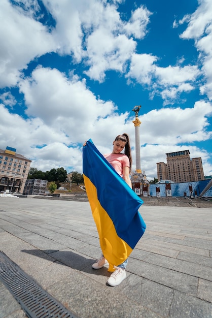 Jonge vrouw met nationale vlag van Oekraïne op straat