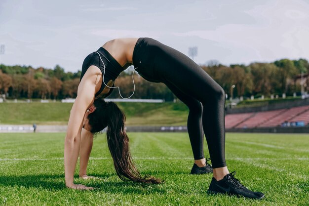 Jonge vrouw met oortelefoonentreinen op het groene stadion