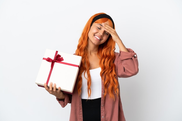 Jonge vrouw met oranje haar die een geschenk vasthoudt dat op een witte achtergrond wordt geïsoleerd en veel lacht