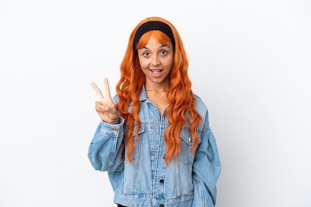 Jonge vrouw met oranje haar geïsoleerd op een witte achtergrond glimlachend en overwinningsteken tonen