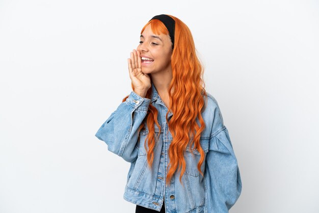 Jonge vrouw met oranje haar geïsoleerd op een witte achtergrond schreeuwend met de mond wijd open naar de zijkant