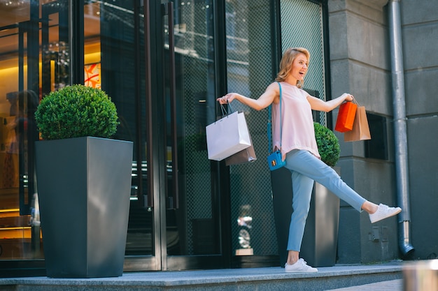 Jonge vrouw met papieren zakken die op verkoopdag de winkel uitloopt